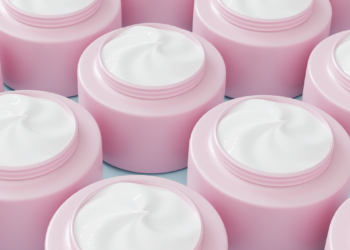 Rows of open pink skin-care jars filled with white cream, shown in close-up