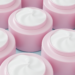 Rows of open pink skin-care jars filled with white cream, shown in close-up